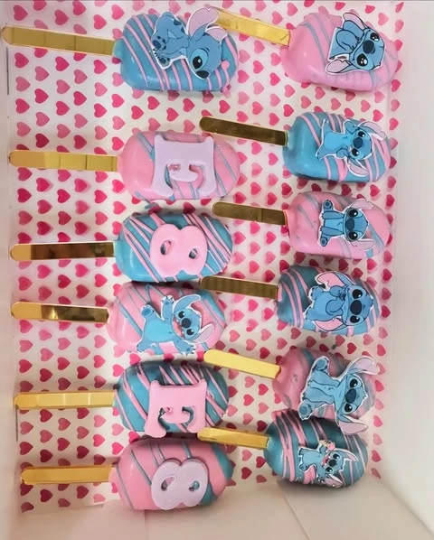Pink and blue Stitch-themed cakesicles on gold sticks with character decorations.