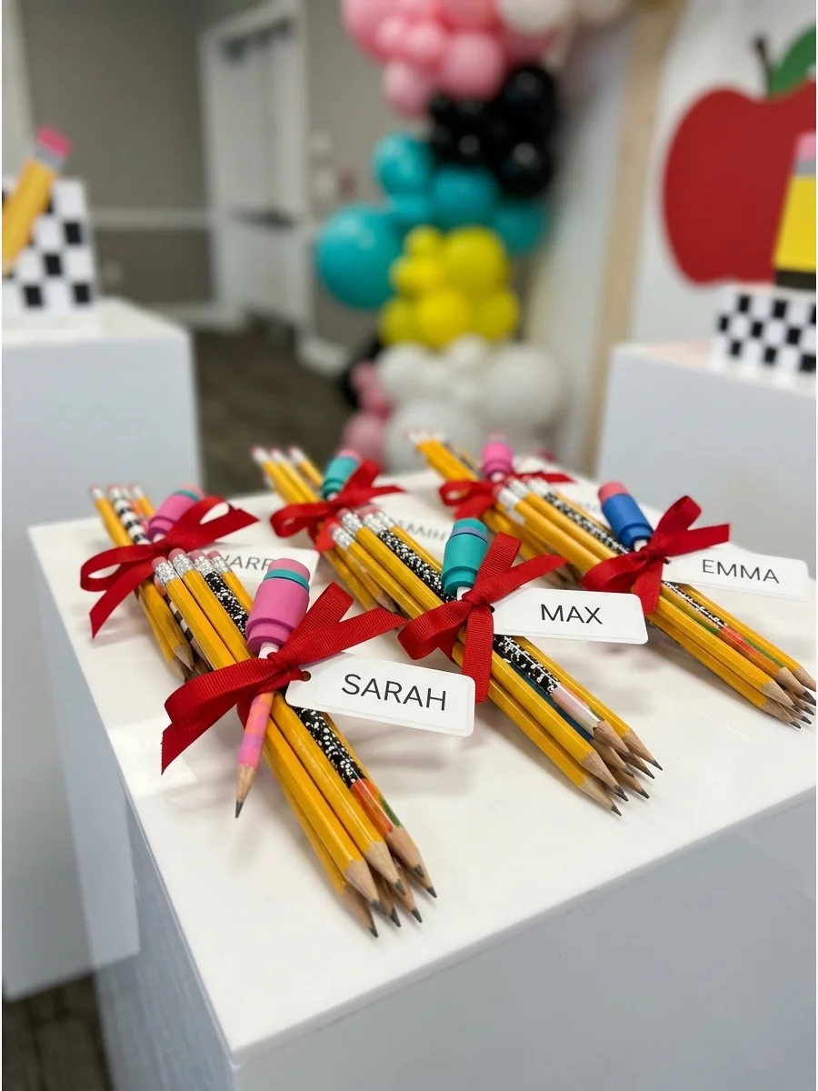 Bundles of yellow pencils tied with red ribbon and personalized name labels.