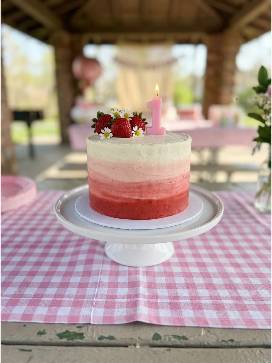 A small smash cake with an ombré frosting transition from red to white.