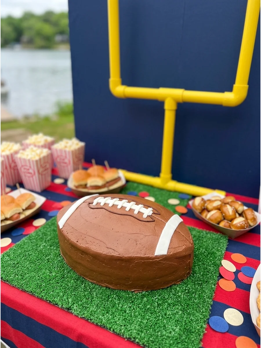 A football-themed party table with a green field cloth and yellow goalpost.