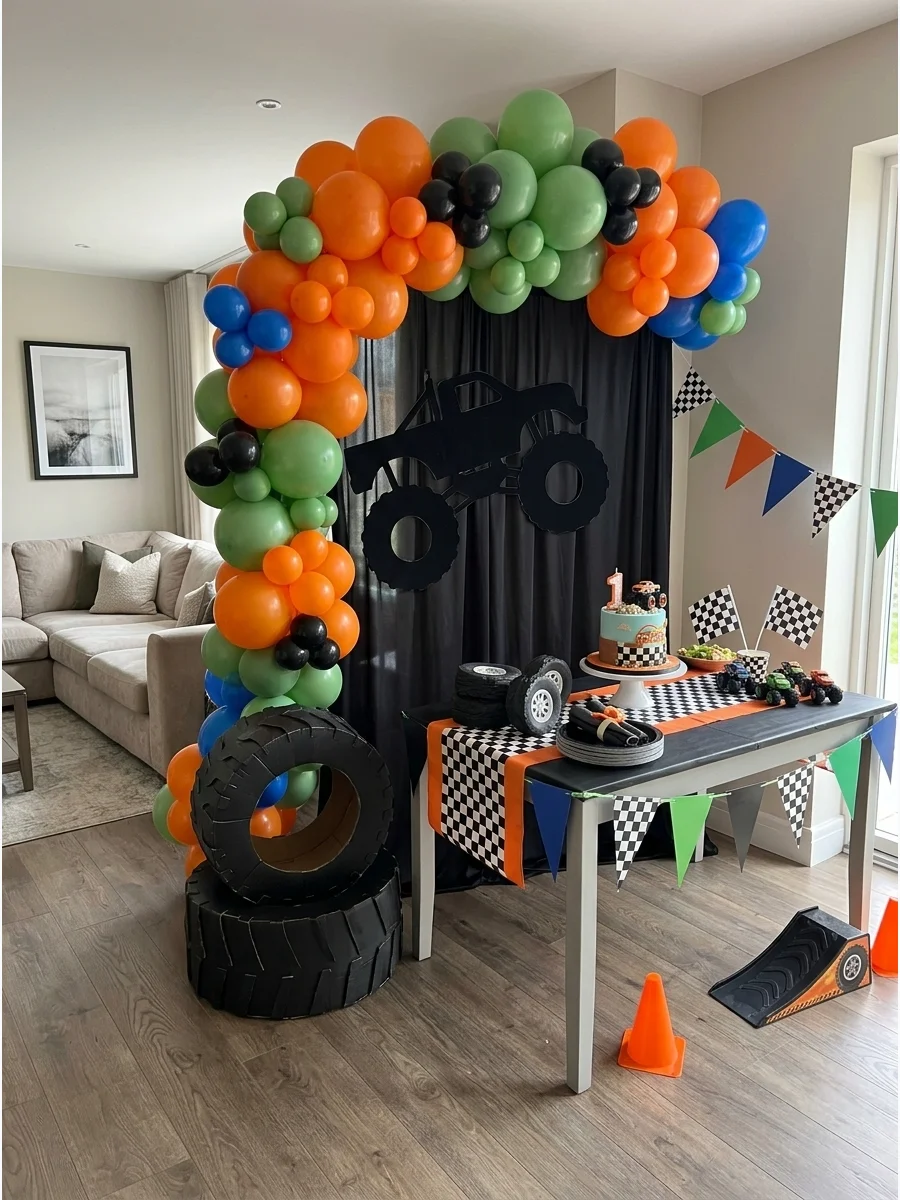 A monster truck birthday theme with orange and green balloons and tire decor.