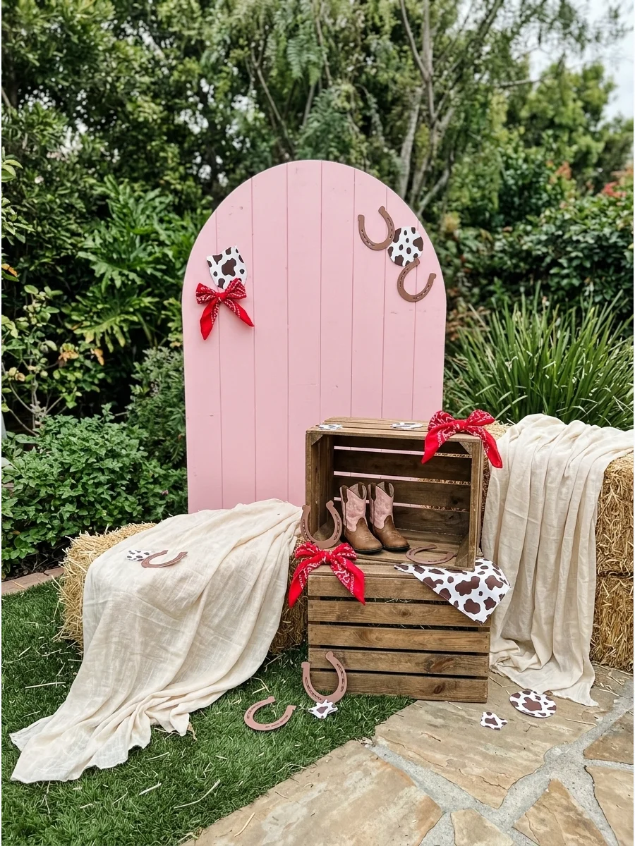 A pink western birthday backdrop with a wooden crate and cowgirl boots.