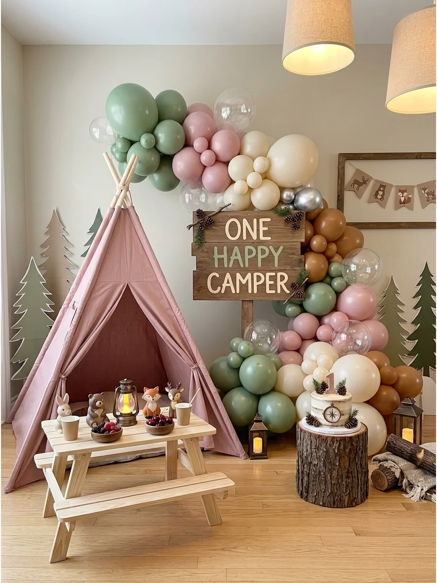 A pink camping theme setup with a small teepee and sage balloons.