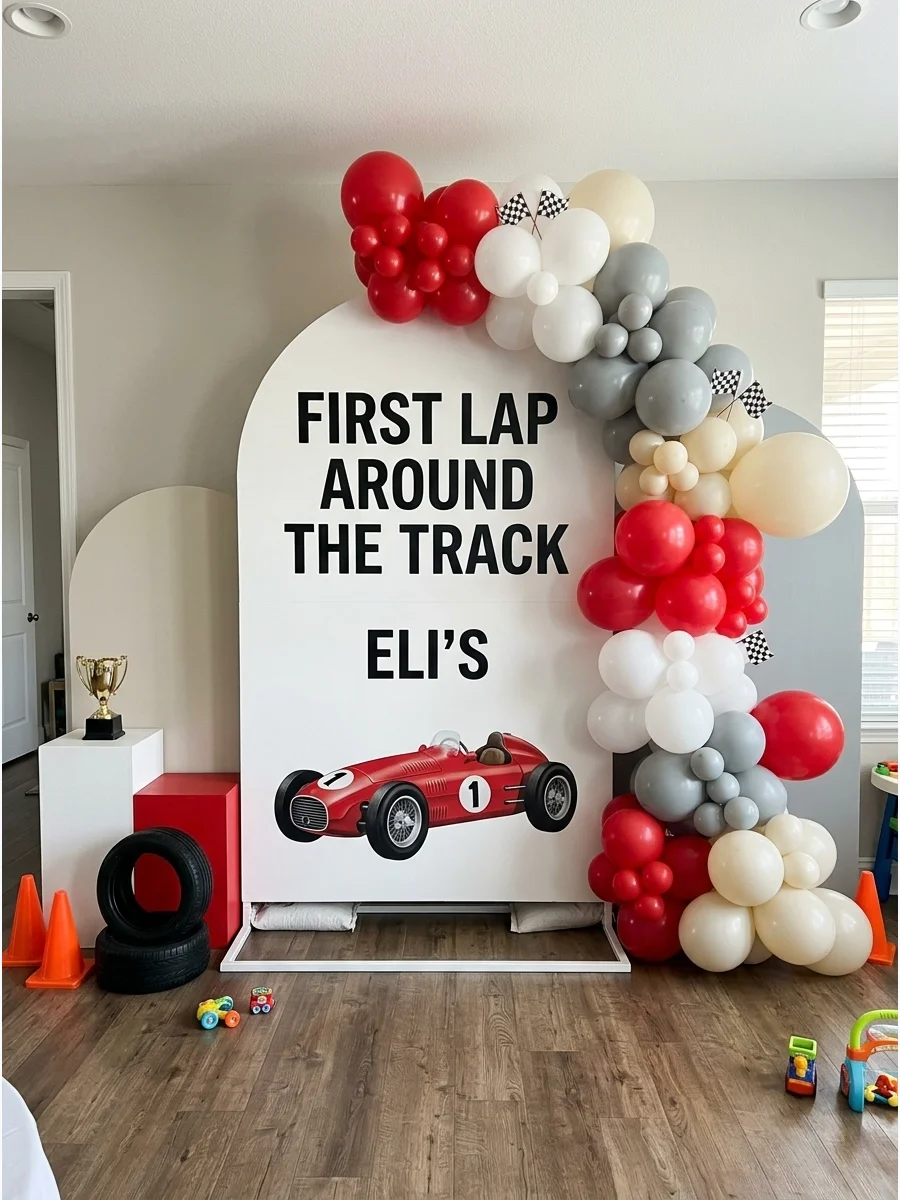 A modern arched backdrop for a first birthday with racing text and a red car.