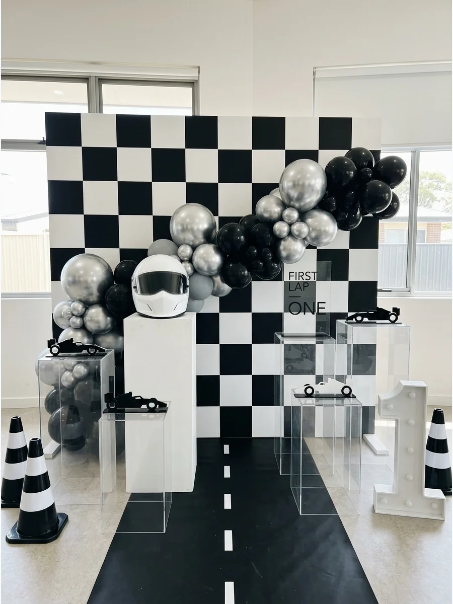 A monochrome racing party setup with checkered patterns and silver chrome balloons.