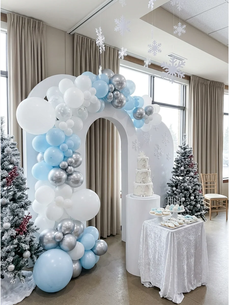 A winter wonderland baby shower setup with white and silver balloons and a white cake.