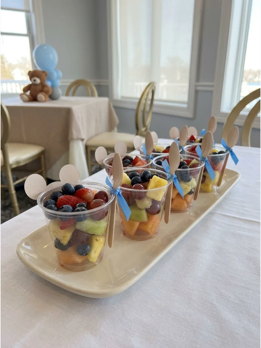 Clear plastic cups filled with fresh fruit and topped with small paper bear ears.