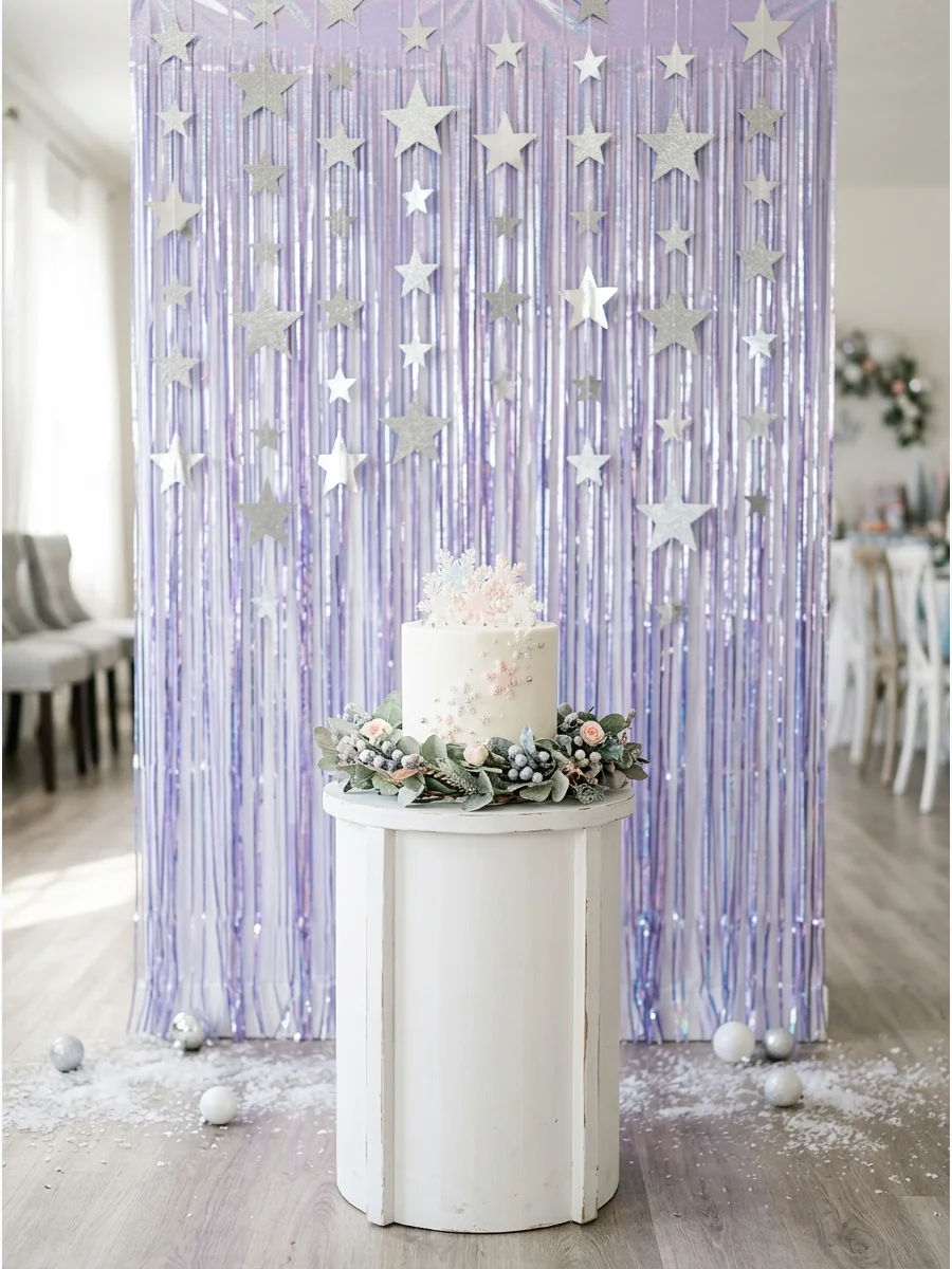 An iridescent lavender fringe backdrop with silver stars and a white cake pedestal.
