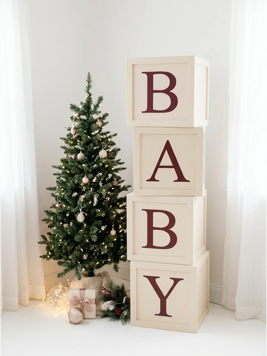 Stacked cream and burgundy baby blocks next to a small Christmas tree.
