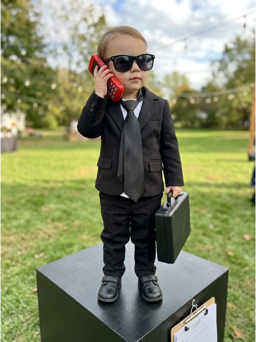 Toddler girl dressed as a CEO with sunglasses and a toy phone.