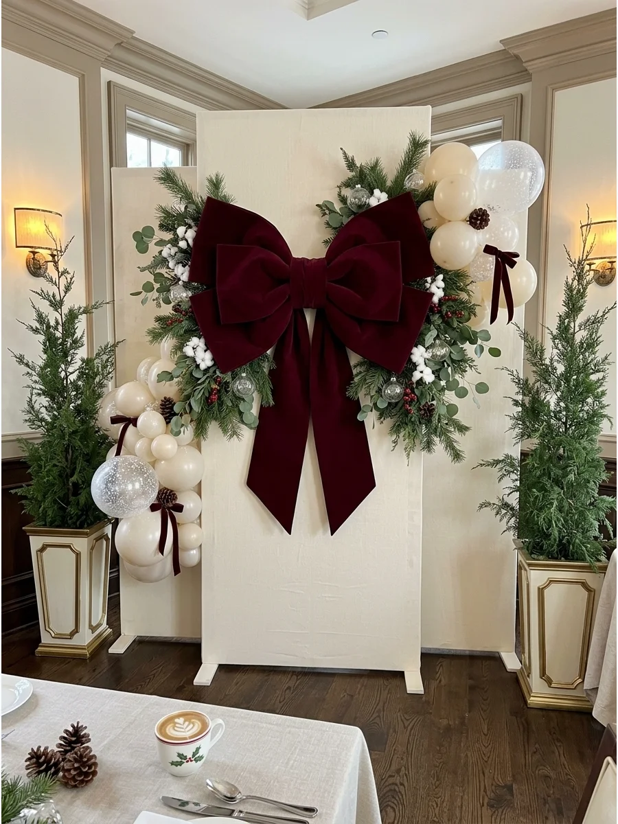 A large burgundy velvet bow on a cream fabric backdrop.