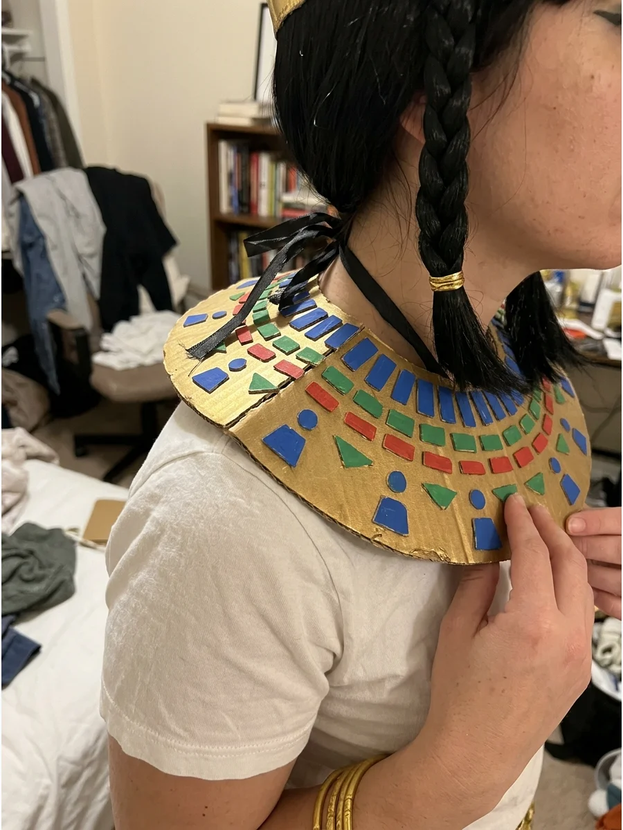 Cardboard Collar Cleopatra Costume. Cut a broad semicircle from lightweight cardboard and cover it with gold paper or paint. Decorate it with geometric rows of blue, red, and green
