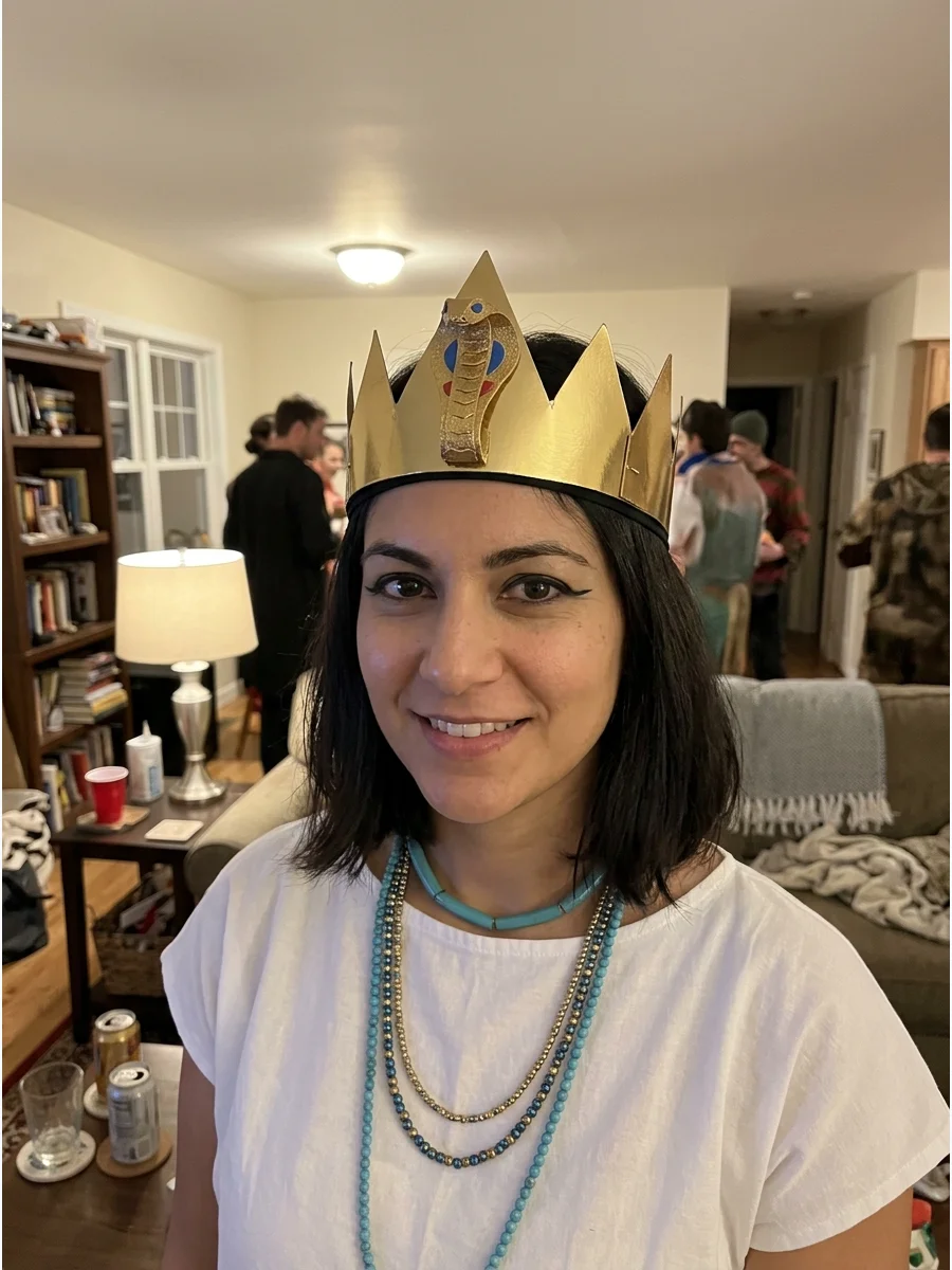 Paper Crown Cleopatra Costume. Make an inexpensive crown from metallic cardstock and add a raised cobra shape in the center. Attach the finished design to a comfortable headband so
