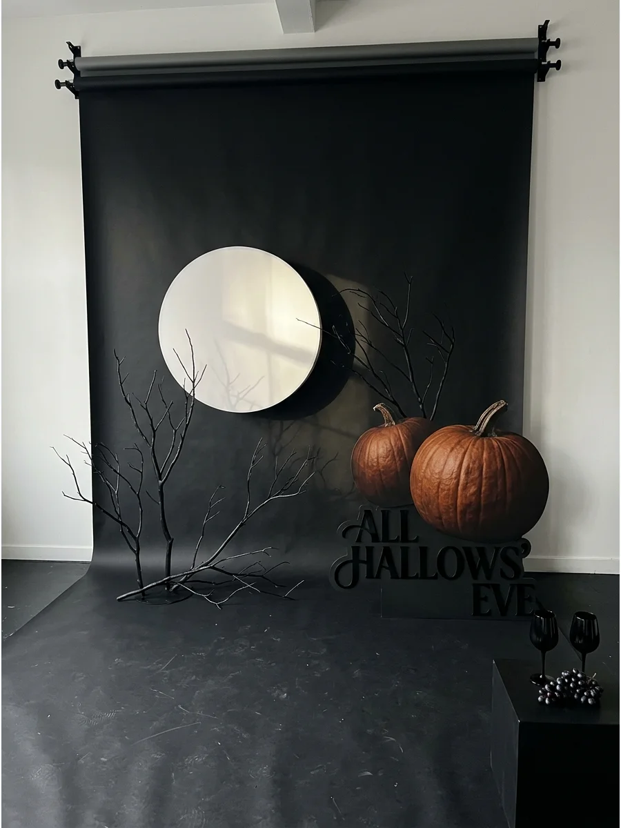 Modern minimalist black backdrop with a large white moon and bare branches.