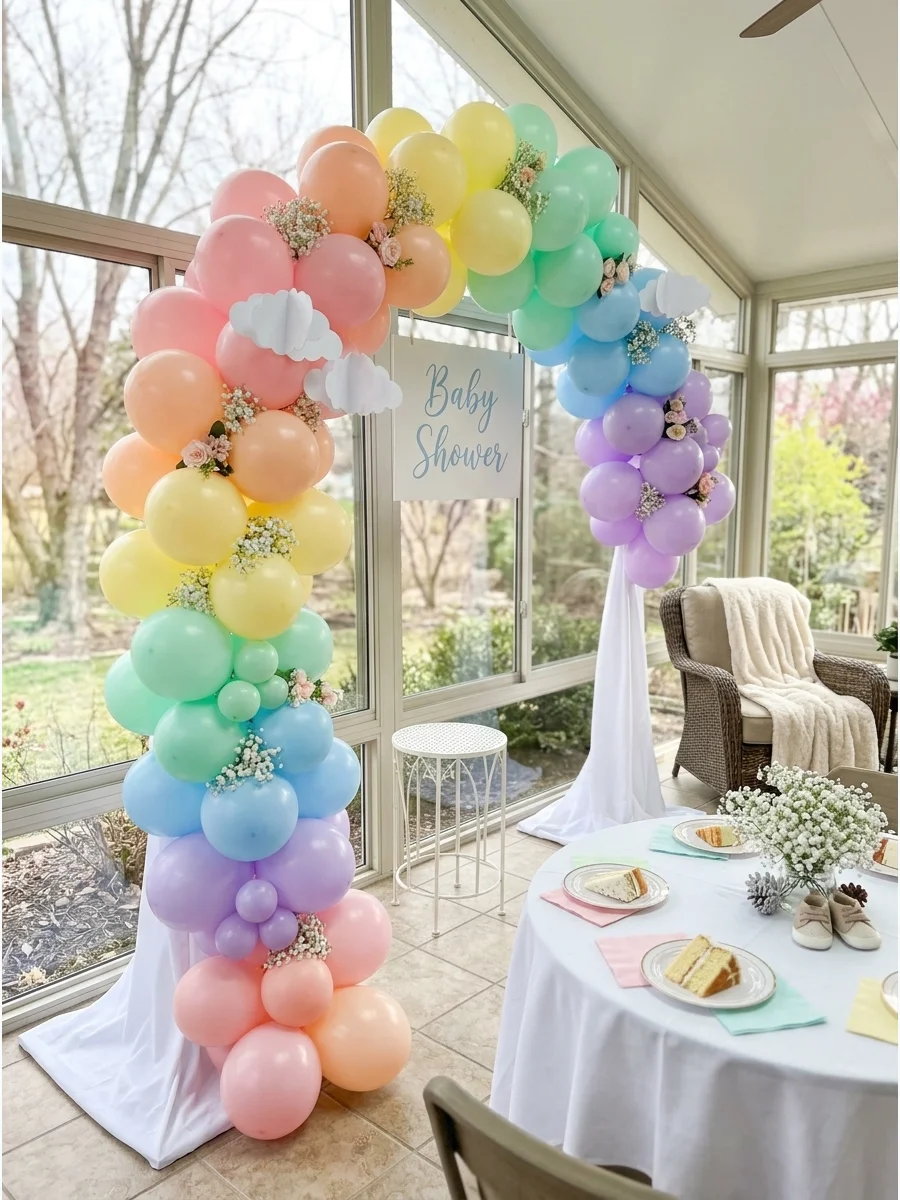 Pastel rainbow balloon arch on an enclosed patio.