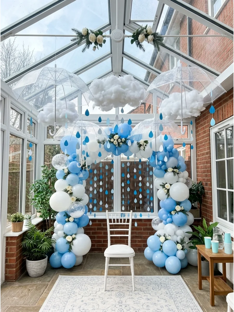 Hanging umbrellas and paper raindrops creating a photo backdrop in a sunroom.