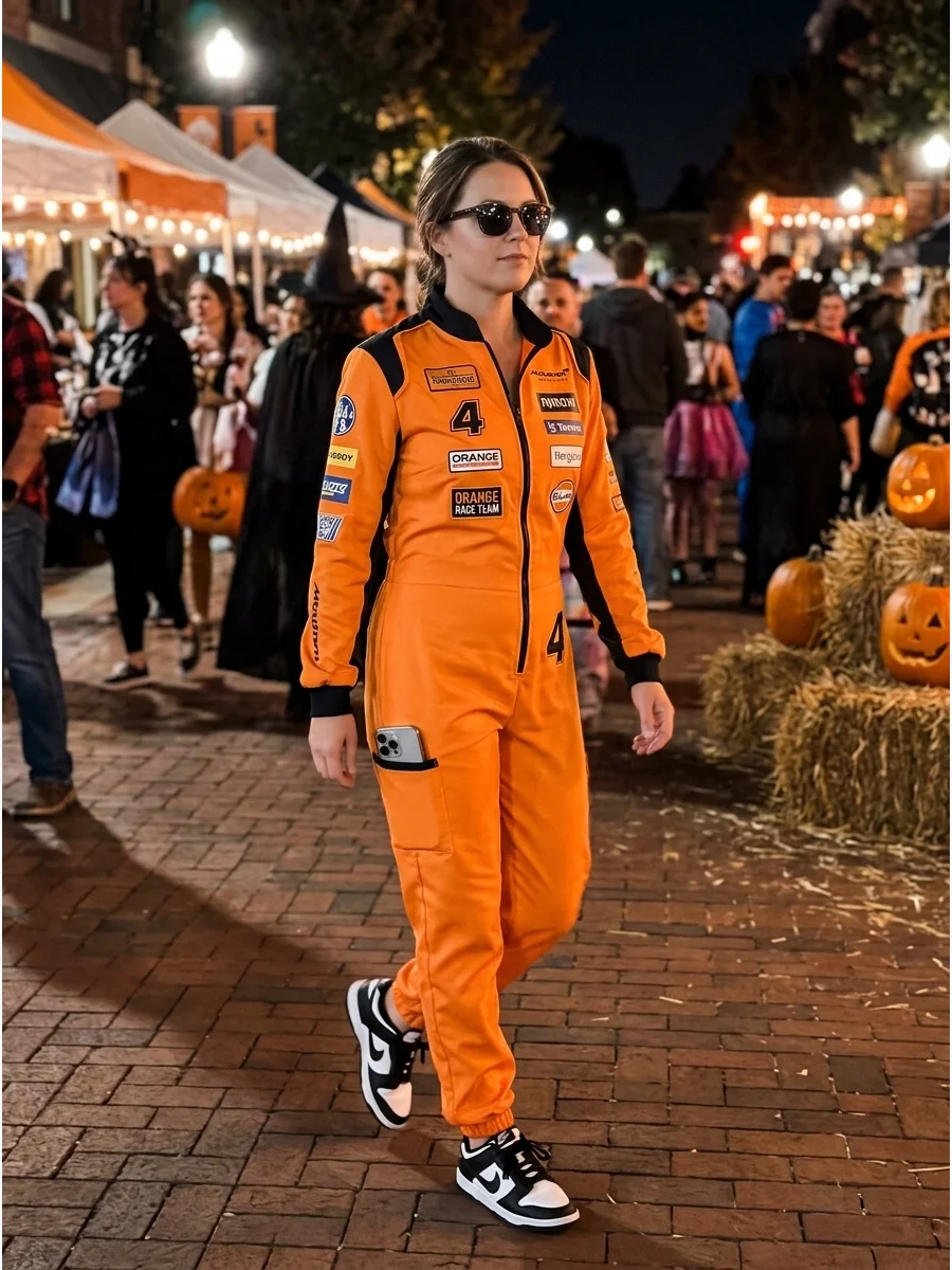 A woman wearing a bright orange and black racing suit at an outdoor event.