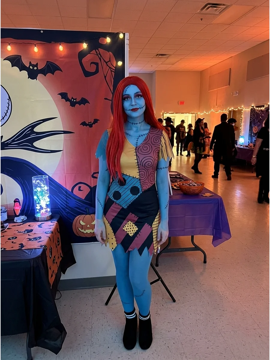 A person wearing a short patchwork mini dress and red wig at a community event.