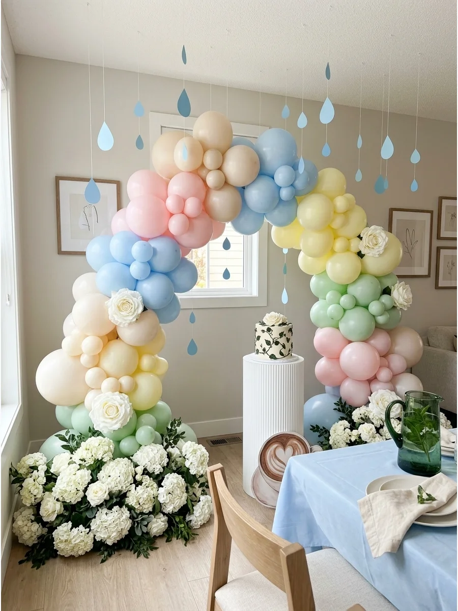 A pastel balloon rainbow with white hydrangea clouds on a wooden floor.