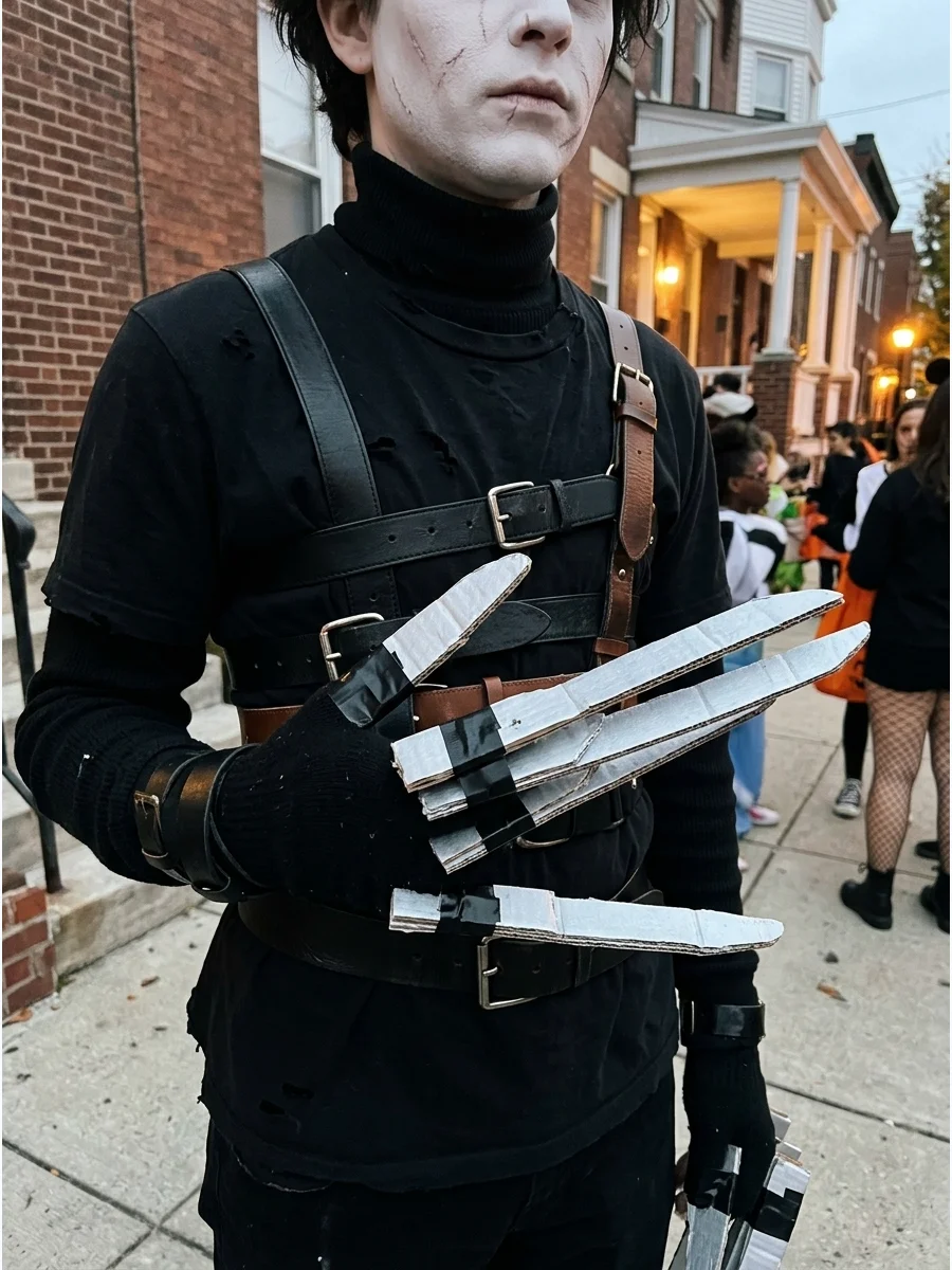 A DIY Edward Scissorhands costume featuring cardboard blades and layered black clothing on a street.