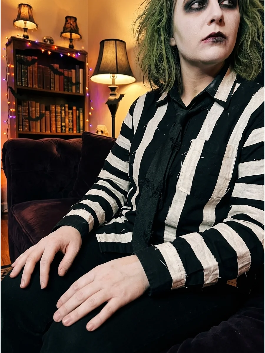 A person in a handmade striped outfit with green hair.