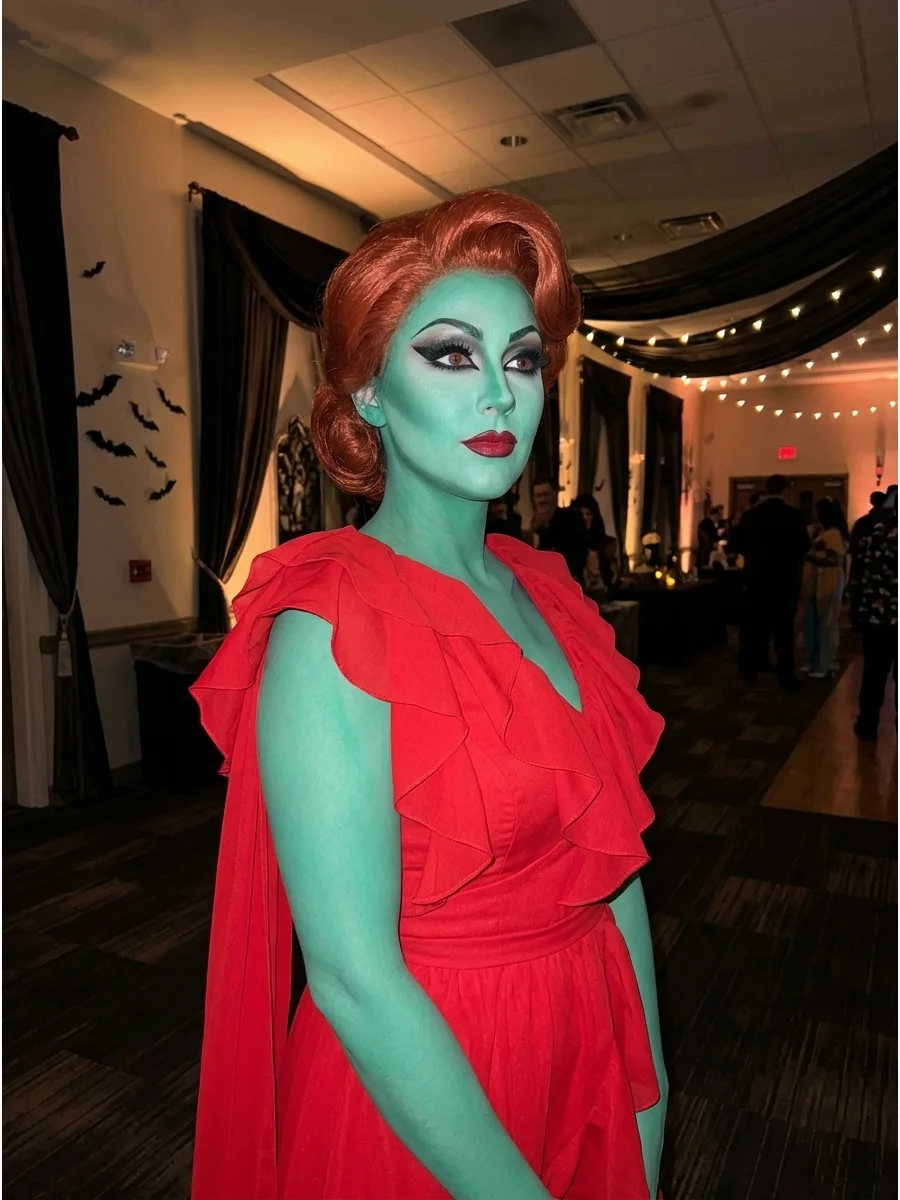A person with teal skin wearing a red dress.
