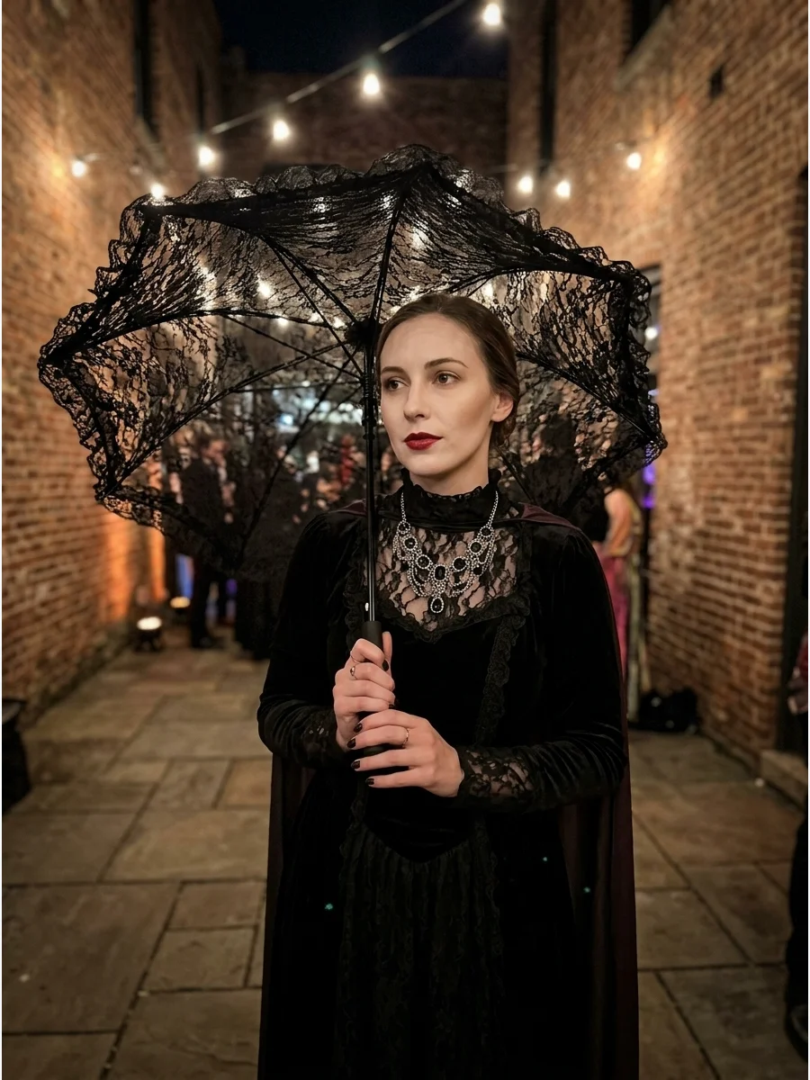 Woman in a black Victorian dress holding a lace parasol.