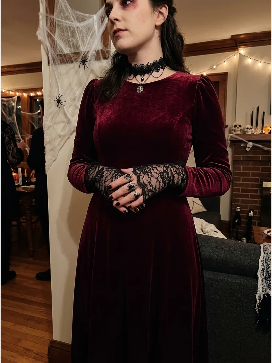 Woman in a burgundy velvet vampire dress with lace gloves.