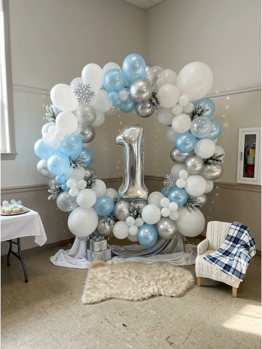A large winter-themed balloon backdrop with a silver number one.