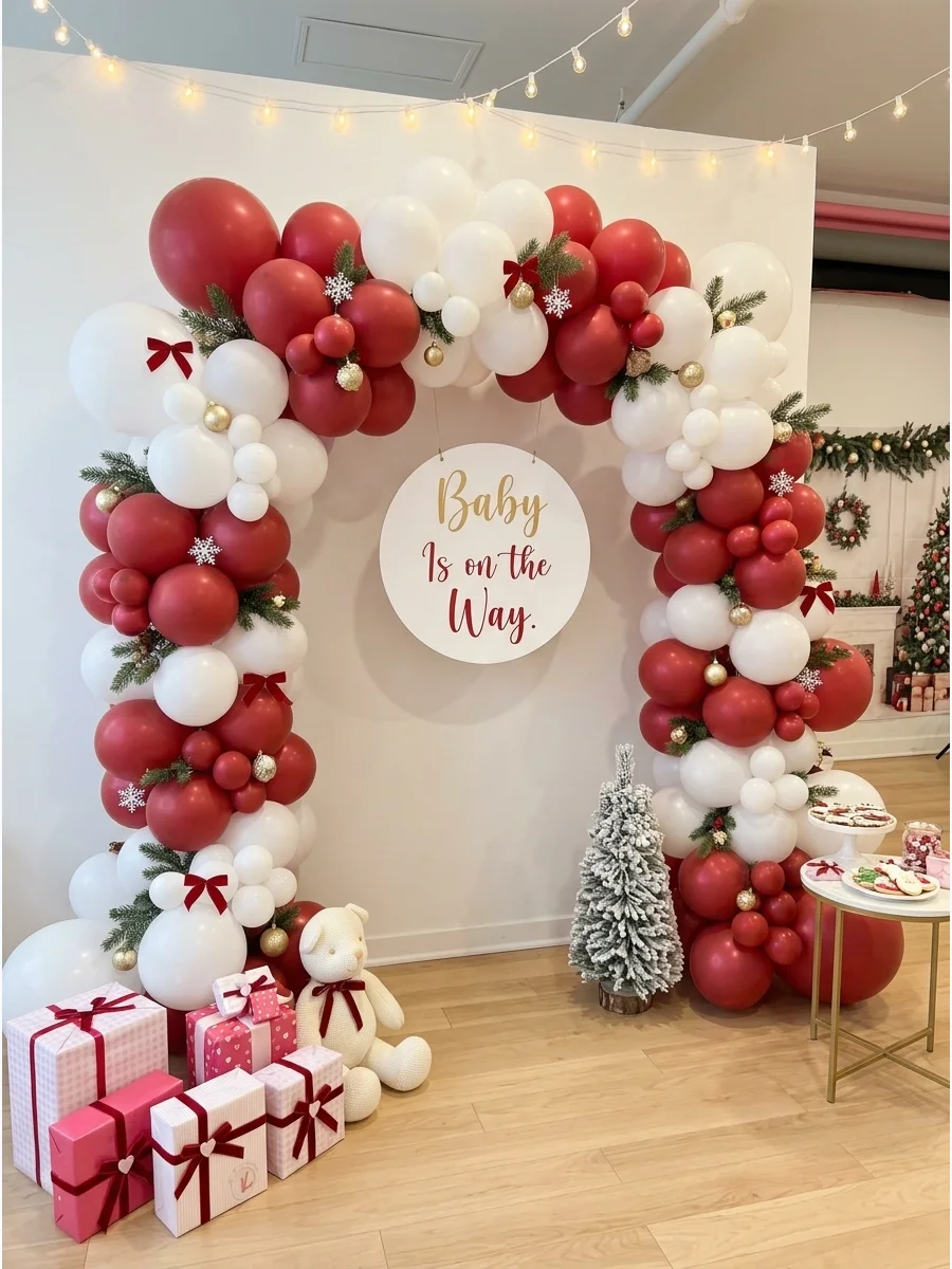 A festive balloon arch with greenery and a baby shower sign.