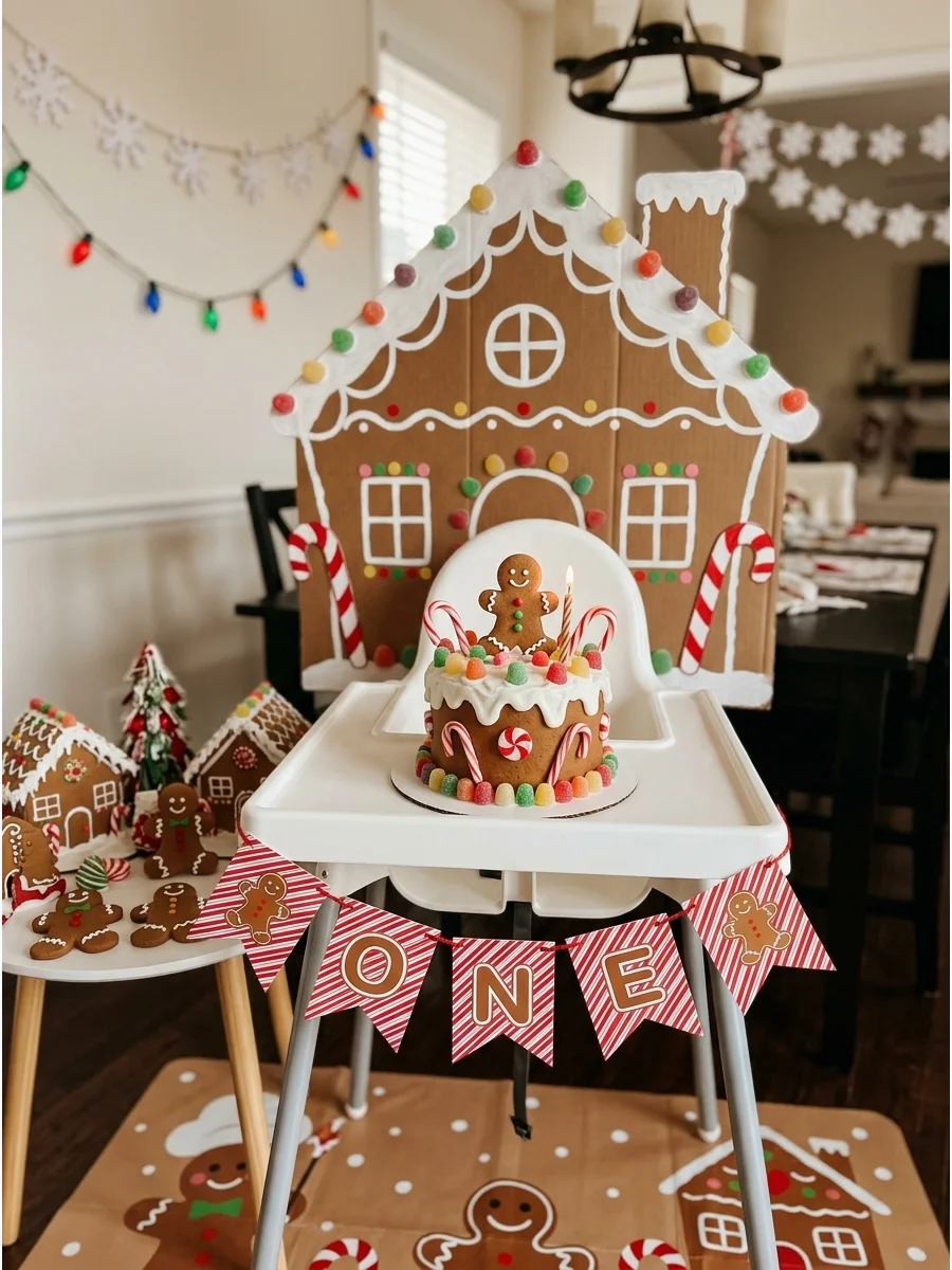 Gingerbread themed first birthday setup with a cardboard house backdrop.