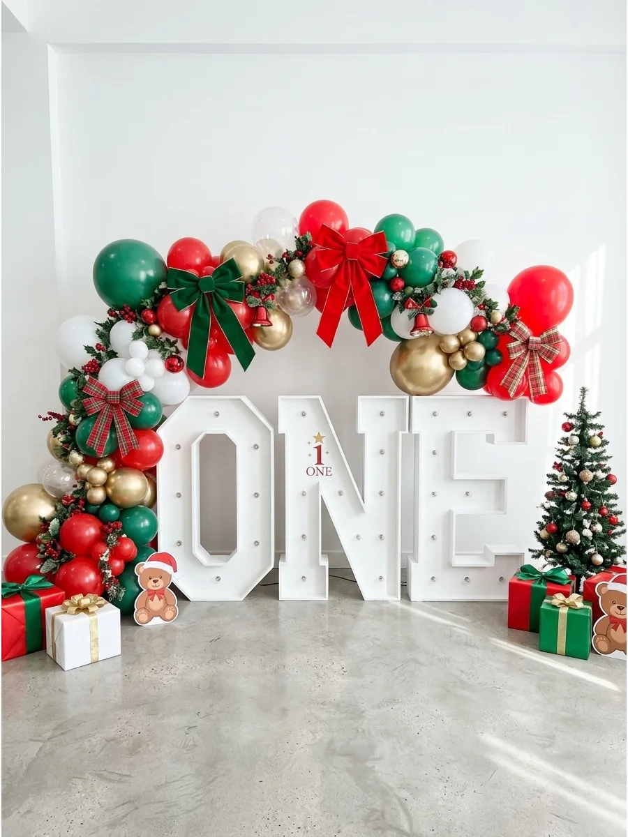 A festive red and green balloon arch surrounding large white letters spelling ONE for a first birthday.