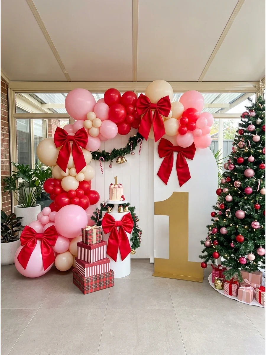 Soft pink and cream balloons with large red bows and a gold number one for a birthday backdrop.
