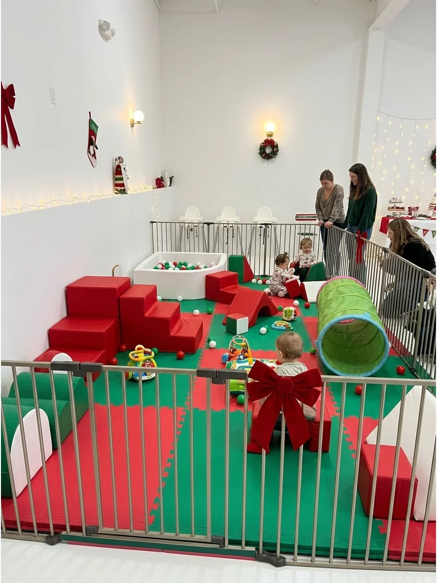 A red and green soft-play area for babies inside a white-walled studio.