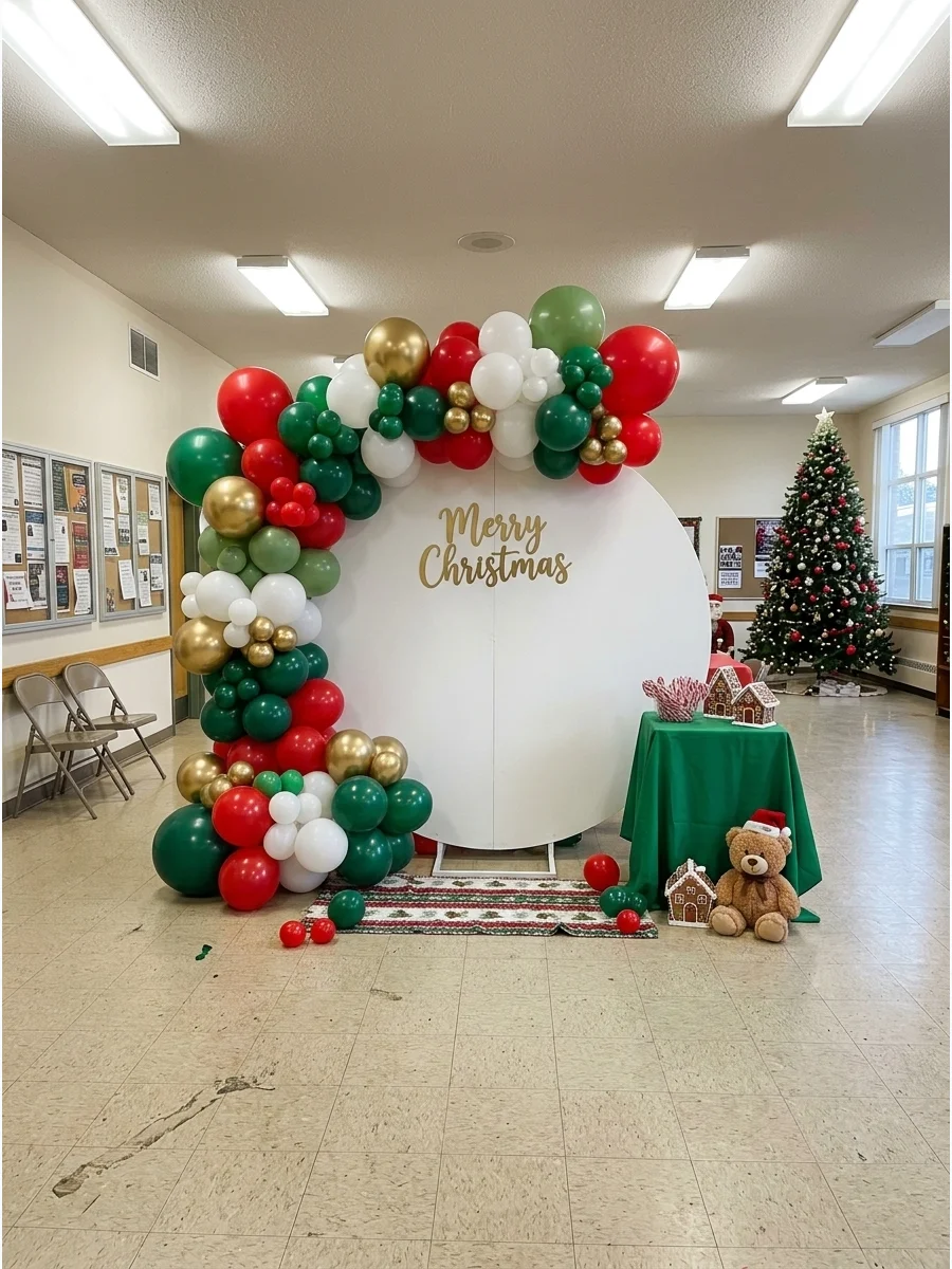 An organic balloon arch in Christmas colors surrounding a white photo backdrop.