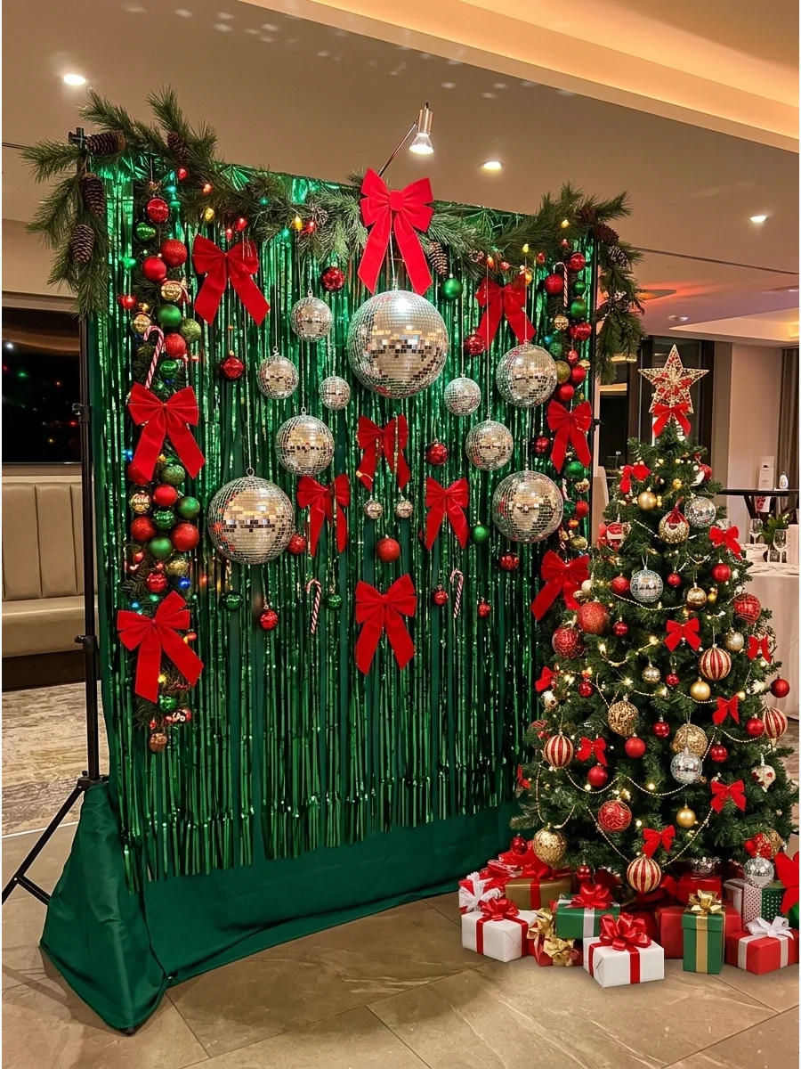 A disco ball and metallic fringe backdrop with green garlands and red bows.