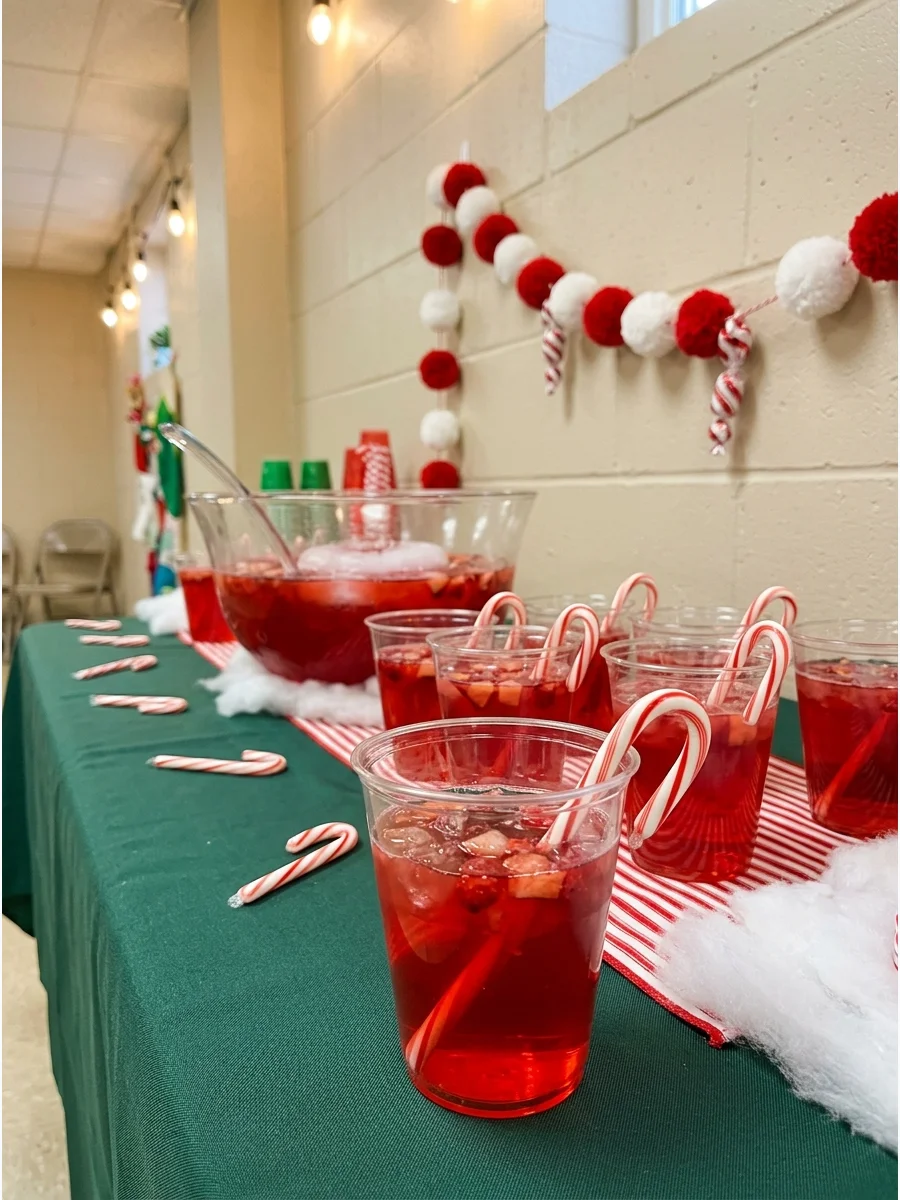 Red punch in a cup with a candy cane stirrer.